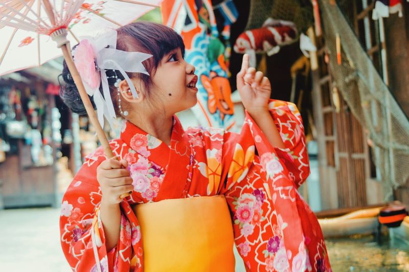 A litle girl wearing a red kimono