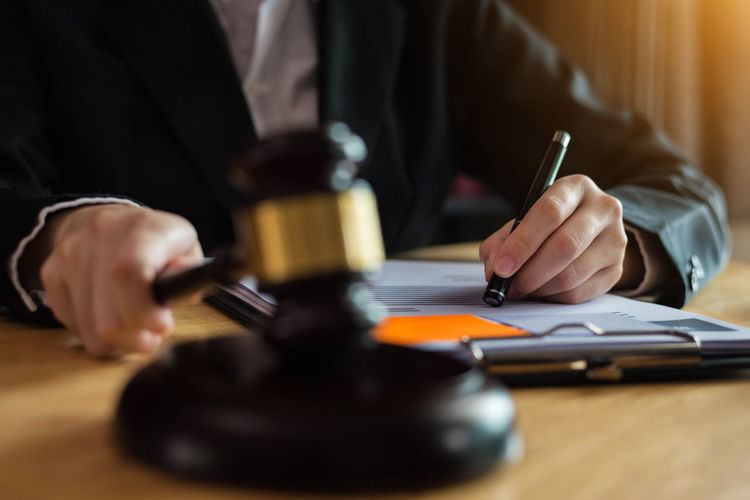 Midsection of lawyer holding gavel on desk in office