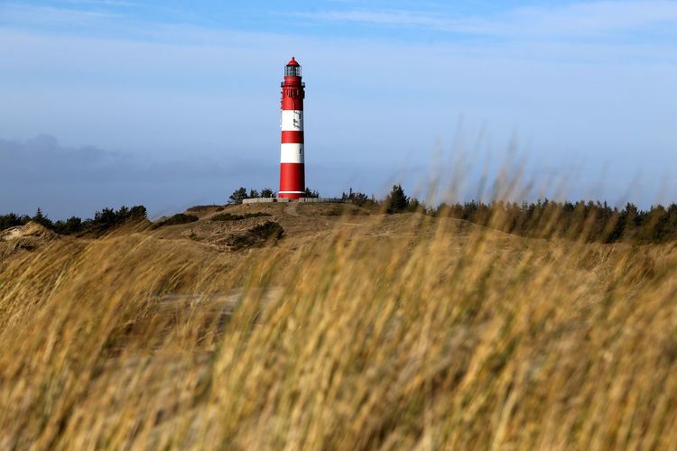 Lighthouse on landscape against sky