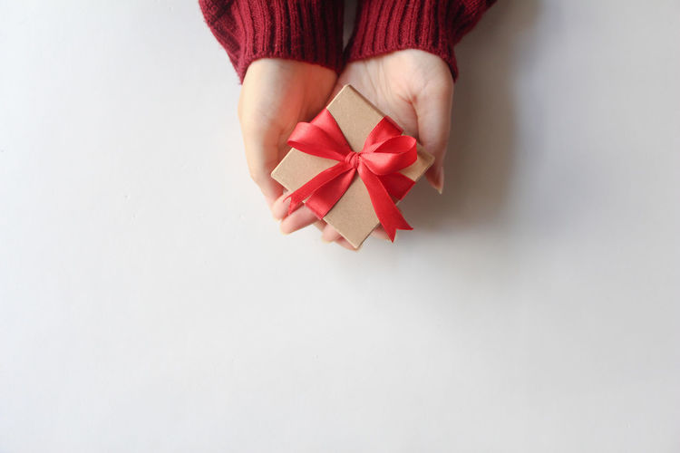 Cropped hand of woman holding gift against white background