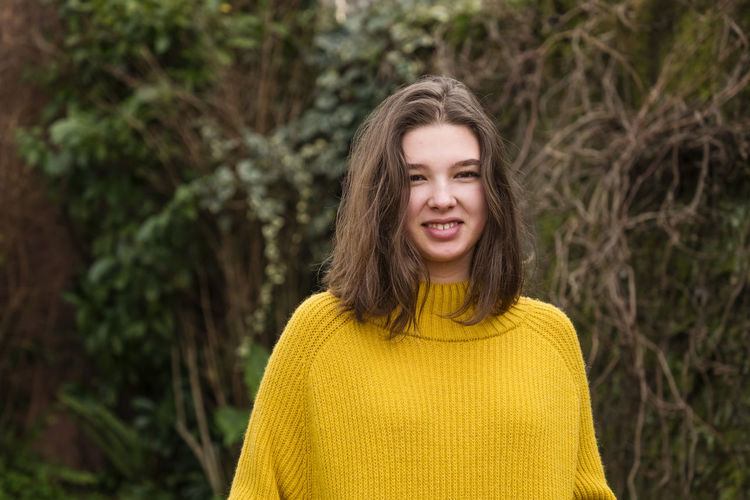 Smiling teenage girl in a yellow sweater outdoors