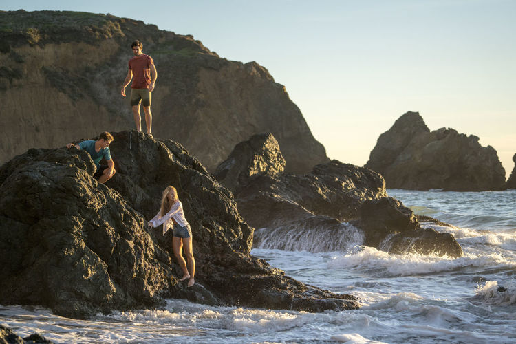 Group of teenagers hanging out on rocks at beach