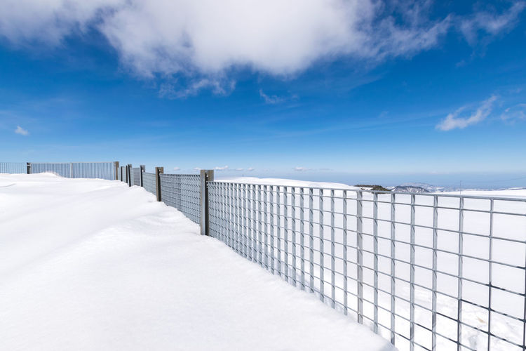 Snow covered railing against sky