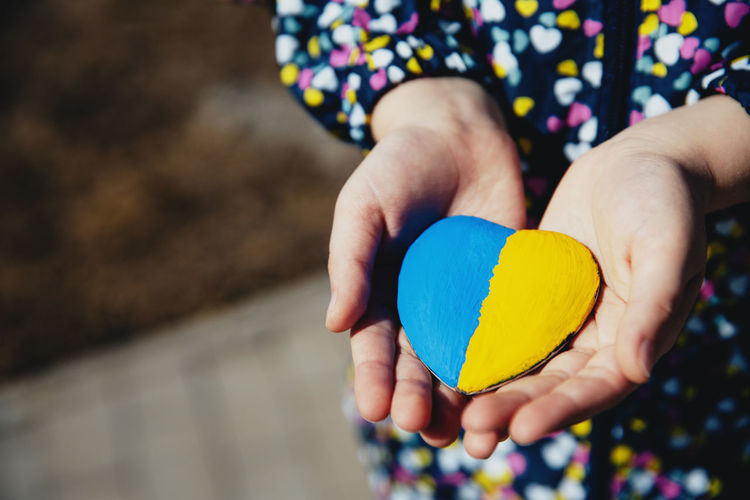 Girl hold heart shaped stone with ukraine blue-yellow national flag anthem. girl love native country