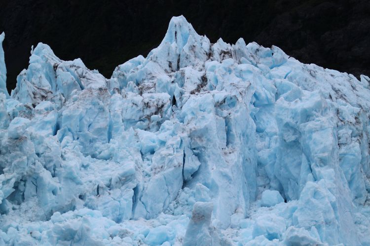 Close-up of beautiful blue glacier ice with a dark background.