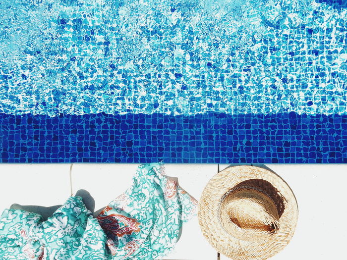 High angle view of sarong and straw hat by swimming pool
