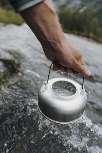 Cropped hand filling water in tea kettle