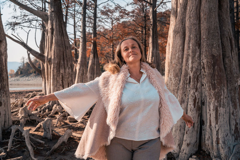 Portrait of mature woman standing against trees