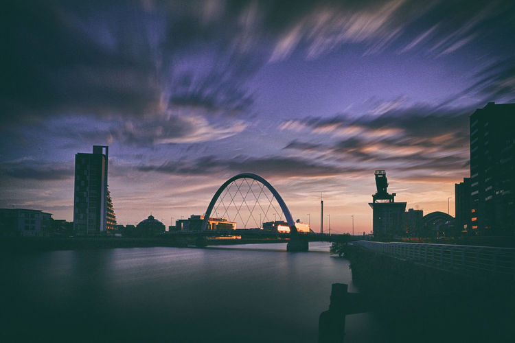 Bridge over river against buildings in city