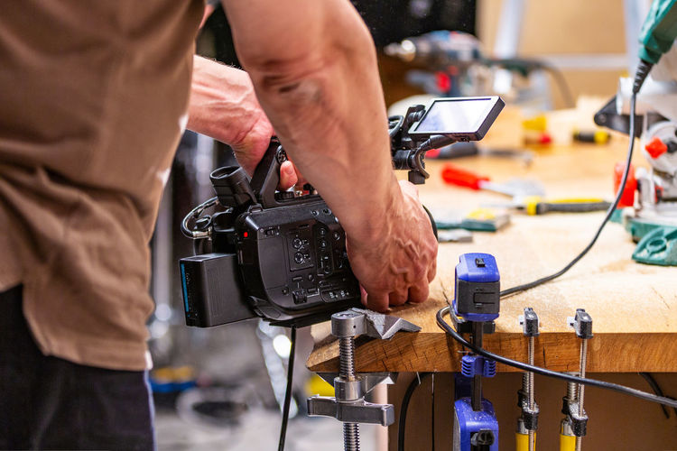 Midsection of man photographing in workshop