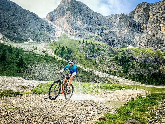 Man riding bicycle on field against mountain