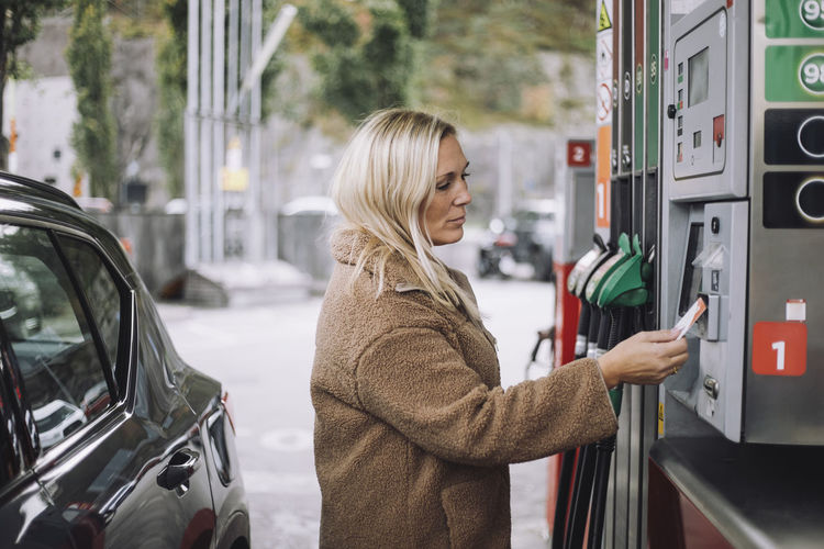 Mature woman doing payment via credit card at fuel station