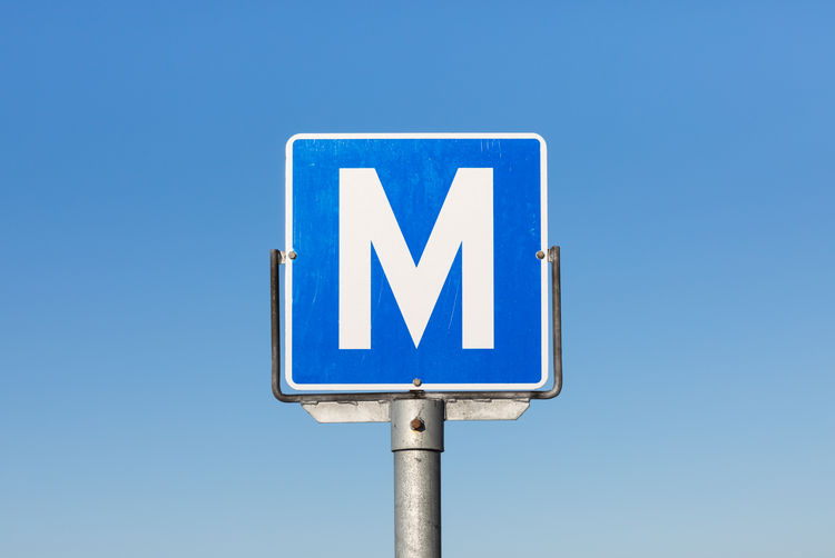 Low angle view of m sign against clear blue sky