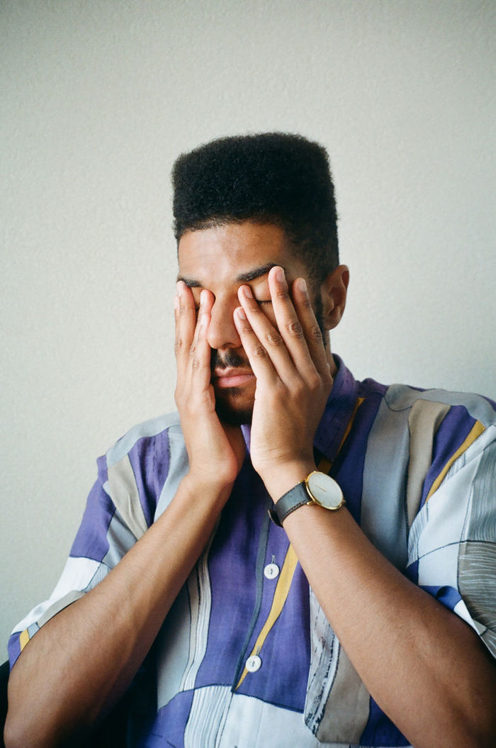 PORTRAIT OF A YOUNG MAN COVERING FACE