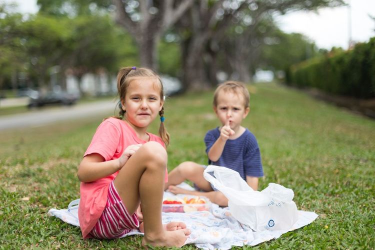 Portrait of smiling boy and girl sitting on grass
