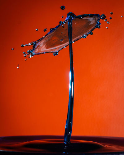 Close-up of water drops on glass against orange background