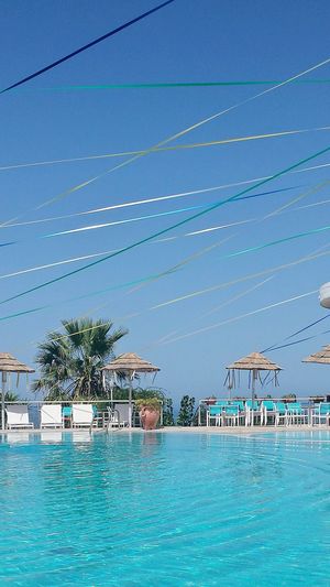 Decoration hanging over blue swimming pool against clear sky