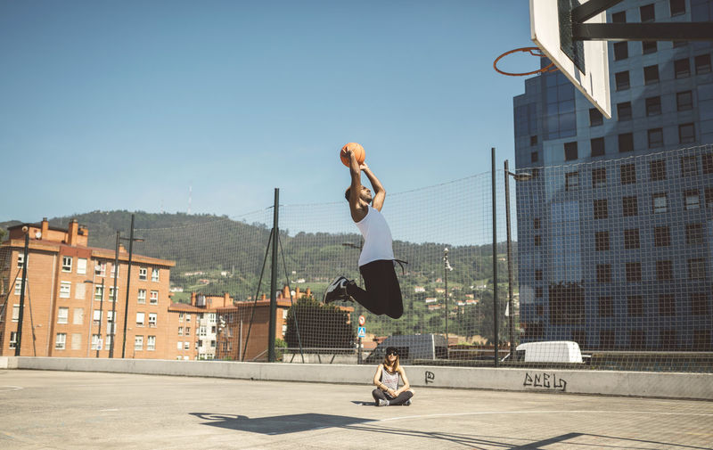 Full length of man skateboarding on city against clear sky