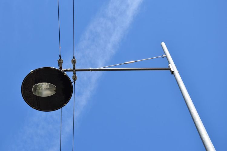 Low angle view of street light and cables against blue sky