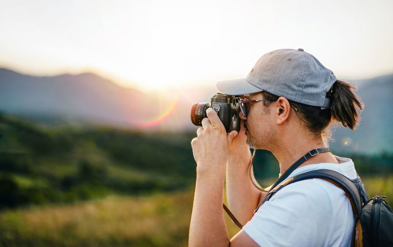 Man taking photos on mountain at sunset
