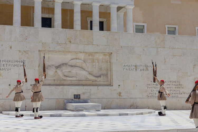 Low angle view of people walking on street, greek soldiers at tomb of the unknown soldier in athens