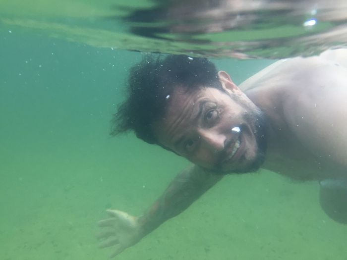 Portrait of shirtless man swimming undersea