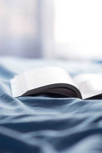 CLOSE-UP OF OPEN BOOK ON BED