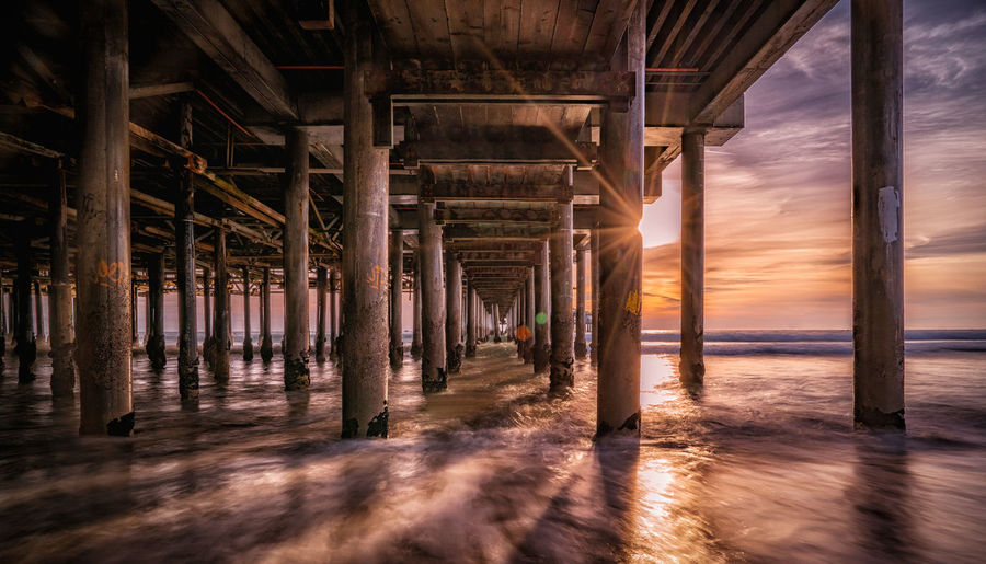 Pier at beach during sunset