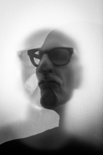 Man in eyeglasses behind glass