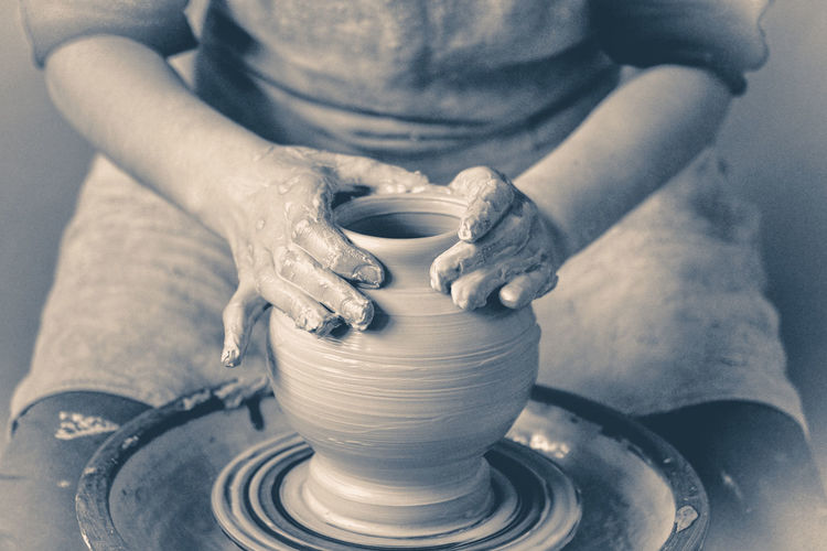 Photo in old vintage style. girl sculpts in clay pot. modeling clay.  man making vessel daytime 