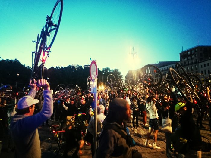 People holding bicycles on street during critical mass event in city