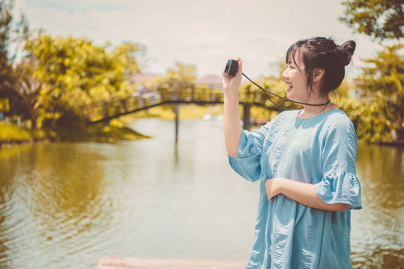 Woman looking at camera while standing by lake