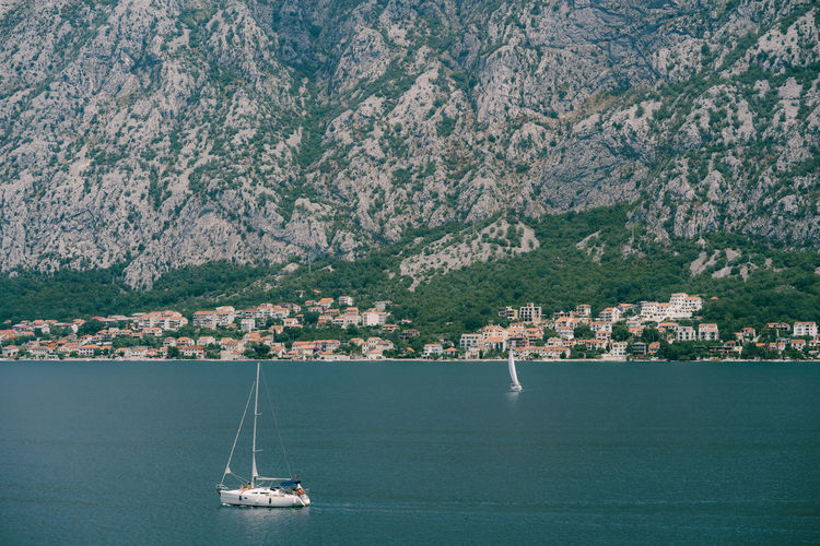 Sailboat sailing on sea by mountain