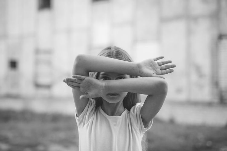 Girl covering face while standing outdoors