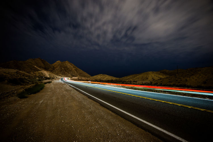 Light trails on highway against sky at night