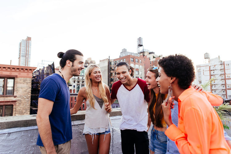 Cheerful friends talking while standing on terrace