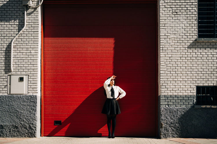 Full length of woman photographing red building