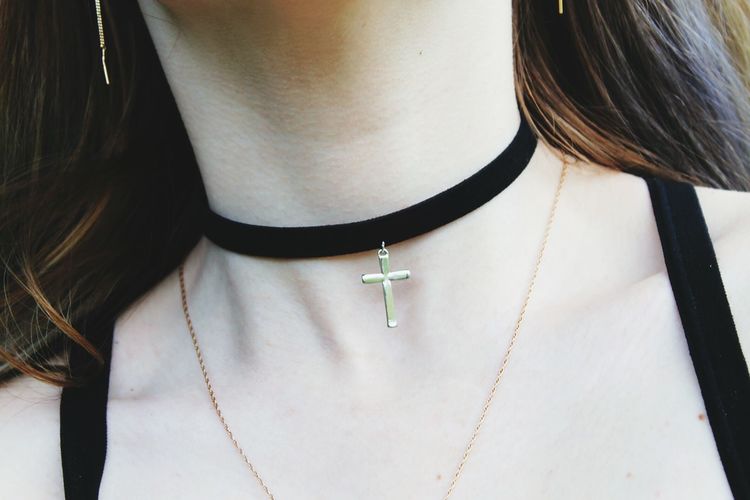 Midsection of woman wearing choker with cross pendant