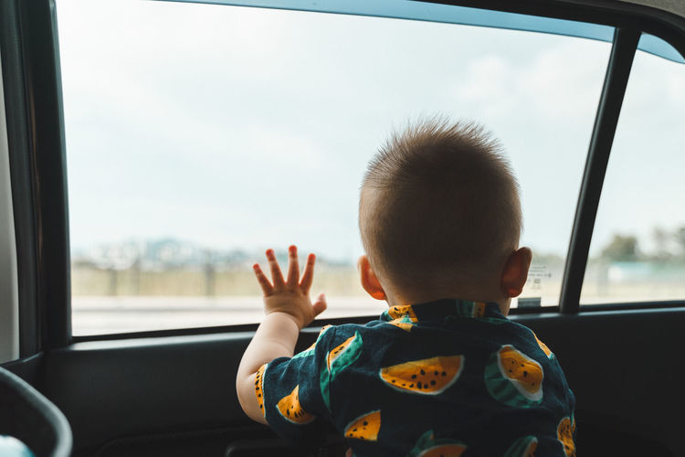 Rear view of boy looking through car window