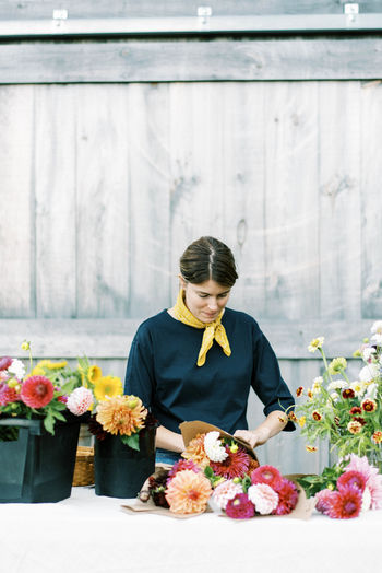 Woman standing by flower bouquet against wall