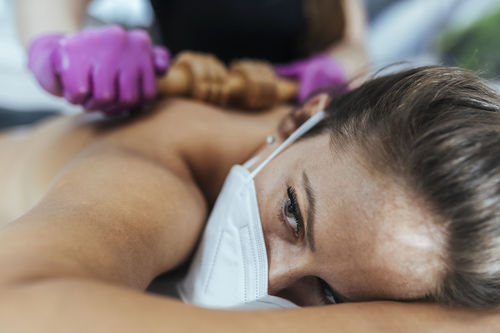 Working safely during coronavirus crisis. masseuse massaging client with gloves and face visor