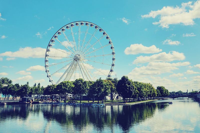 Ferris wheel by lake against sky