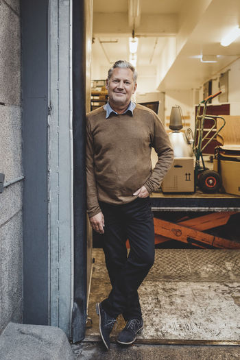 Full length portrait of mature businessman standing in new office