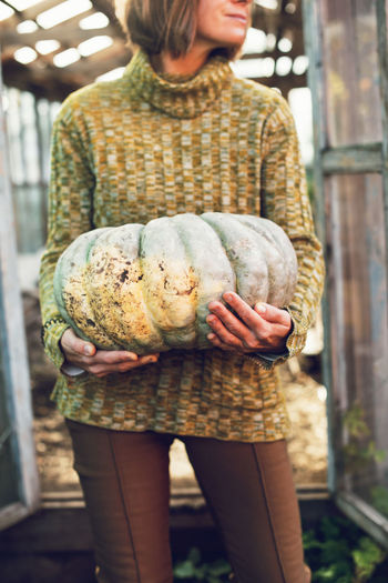 Young woman holding in her hands big ripe pumpkin yields from garden. thanksgiving halloween