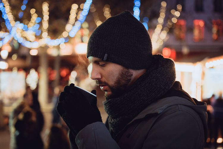Man drink a hot wine at christmas village with lights