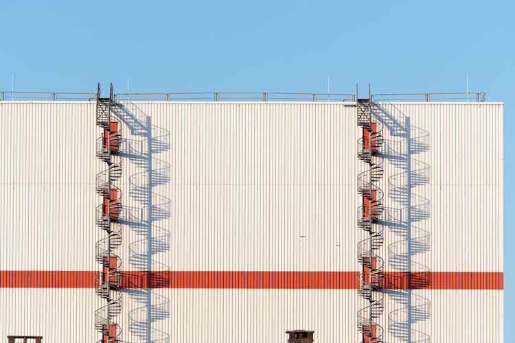 Fire escape on metallic structure against clear blue sky