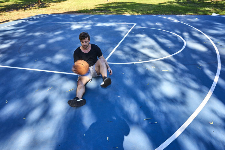 Full length of man sitting on basketball court