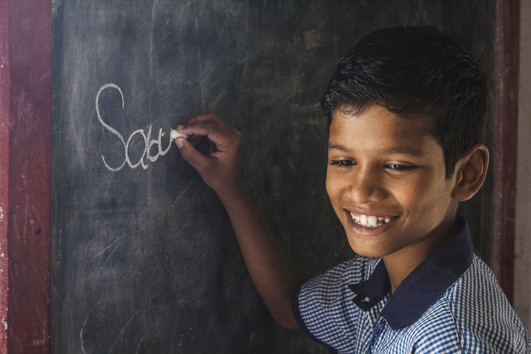 Close-up of boy writing on blackboard