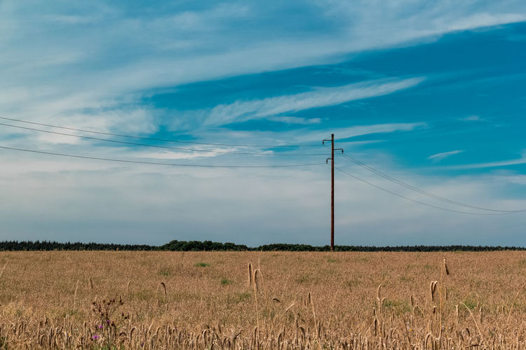 Electricity pylon on field against sky