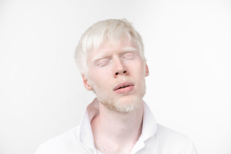 Close-up of man with eyes closed standing against white background